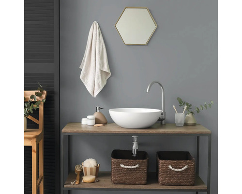 Moderne badkamer met witte opzetwastafel op een houten wastafelmeubel, hoge kraan, zeshoekige spiegel en gevlochten manden.