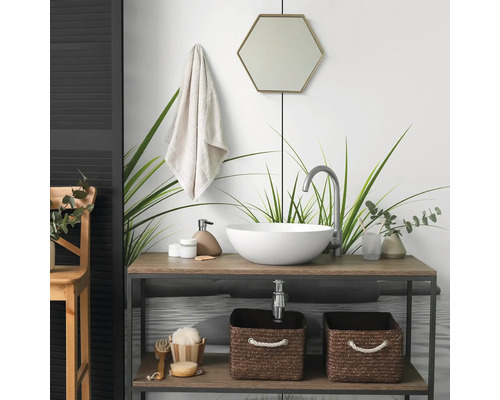Moderne badkamer met een ronde opzetwastafel op een houten wastafelmeubel, een hoge kraan, een zeshoekige spiegel en gevlochten opbergmanden.
