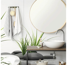 Moderne badkamer met ronde spiegel, witte opzetwastafel op een houten wastafelblad en een glazen wand met gras- en steenmotieven.