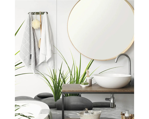 Moderne badkamer met ronde spiegel, witte opzetwastafel op een houten wastafelblad en een glazen wand met gras- en steenmotieven.