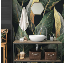 Fotobehang met grote botanische bladeren in de badkamer achter een houten wastafelmeubel met witte opzetkom en accessoires.