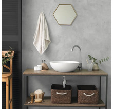 Moderne badkamer met een witte opzetwastafel op een houten consoletafel. Inclusief gebogen kraan, zeshoekige spiegel en gevlochten manden.