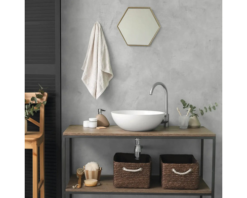 Moderne badkamer met een witte opzetwastafel op een houten consoletafel. Inclusief gebogen kraan, zeshoekige spiegel en gevlochten manden.
