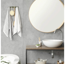 Moderne badkamer met ronde spiegel, witte waskom op een houten wastafelblad en grijze wand met betonlook.