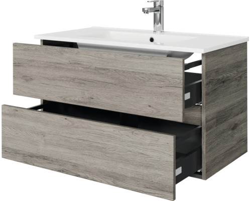 Wastafelonderkast met twee geopende laden in houtlook inclusief witte wastafel en verchroomde kraan.