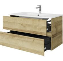 Wastafelonderkast met twee geopende laden in houtlook, witte wastafel en verchroomde kraan.