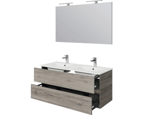 Dubbele wastafel met onderkast in houtlook, twee kranen en grote spiegel met verlichting.