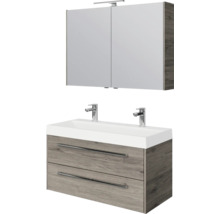 Badkamermeubelset: wastafelonderkast in houtlook met twee laden, dubbele wastafel met twee kranen en spiegelkast met verlichting.