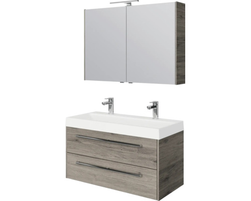 Badkamermeubelset: wastafelonderkast in houtlook met twee laden, dubbele wastafel met twee kranen en spiegelkast met verlichting.
