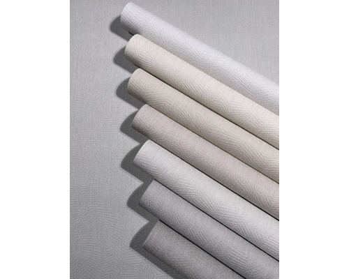 Diverse behangrollen in neutrale tinten met een gestructureerd oppervlak en zigzagpatroon.