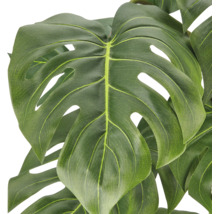 Close up van een kunstmatige Monstera plant met gedetailleerde bladstructuur.