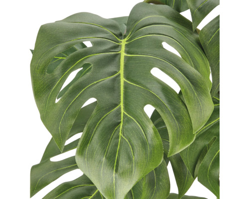 Close up van een kunstmatige Monstera plant met gedetailleerde bladstructuur.