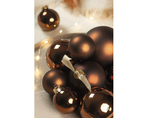 Bronskleurige kerstballen in matte en glanzende uitvoering, gerangschikt met een decoratieve lichtslinger.