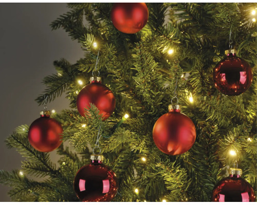 Kerstboom versierd met matte en glanzende rode kerstballen en warmwitte LED-lampjes.