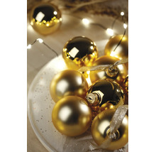 Feestelijke opstelling van gouden kerstballen in glanzende en matte uitvoering op een wit bord met LED-lichtsnoer en decoratielint.