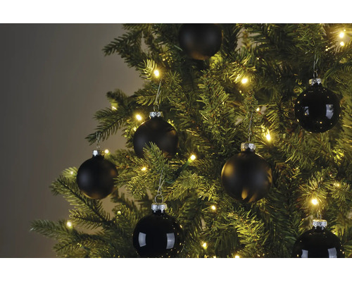 Kerstboom met warmwitte verlichting en zwarte kerstballen in matte en glanzende uitvoering.