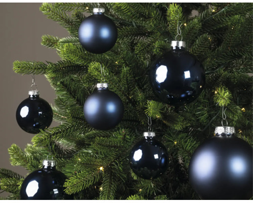 Blauwe kerstballen in verschillende maten, deels mat en deels glanzend, aan een groene kerstboom.