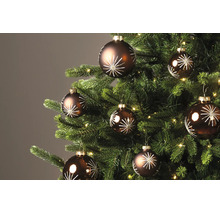 Bruine kerstballen met wit sterrenpatroon aan een versierde kerstboom met verlichting.