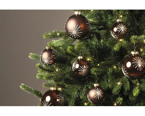 Bruine kerstballen met wit sterrenpatroon aan een versierde kerstboom met verlichting.