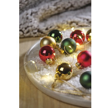 Feestelijke opstelling van kerstballen in rood, groen en goud op een dienblad met kunstsneeuw en LED-lichtsnoer.
