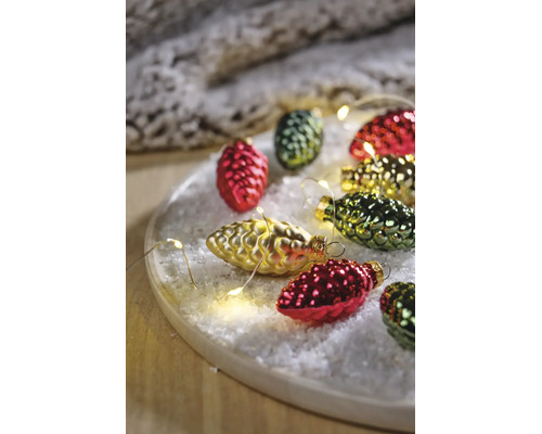 Kerstdecoratie in de vorm van dennenappels op kunstsneeuw met een lichtsnoer op een houten dienblad.