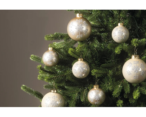 Kerstballen met glinsterend sneeuwvlokpatroon aan de takken van een kerstboom.