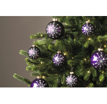 Paarse kerstballen met glinsterend sneeuwvlokpatroon aan een kerstboom met lichtjes.