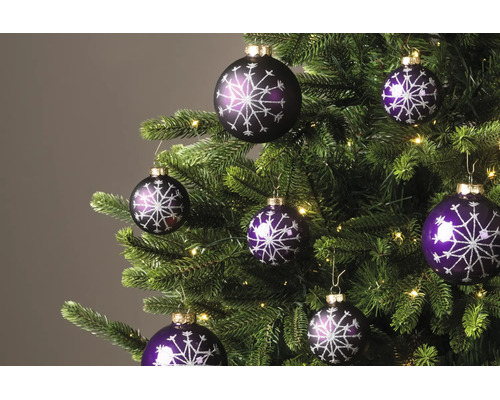 Paarse kerstballen met glinsterend sneeuwvlokpatroon aan een kerstboom met lichtjes.