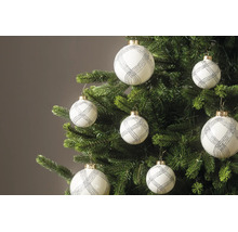 Witte kerstballen met zilveren glitterpatroon hangen aan de takken van een groene kerstboom.