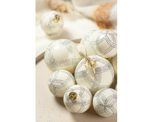 Witte kerstballen met zilveren glitterpatronen en gouden kapjes in verschillende maten.