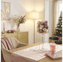 Feestelijke kerstkamer met eettafel, glazen bokaal vol kerstversiering, gedecoreerde kerstboom en dressoir.