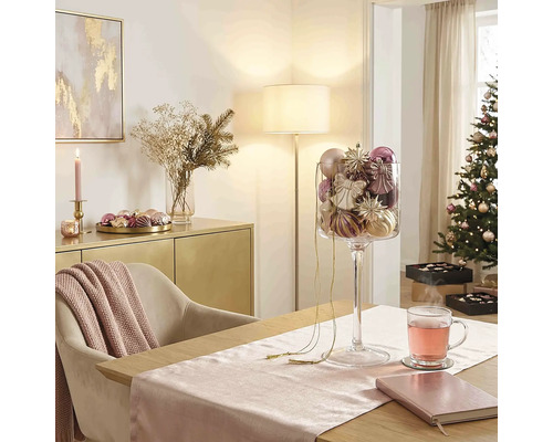 Feestelijke kerstkamer met eettafel, glazen bokaal vol kerstversiering, gedecoreerde kerstboom en dressoir.