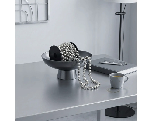 Zilverkleurige kettingsnoer op een rol in een grijze schaal op een licht, georganiseerd bureau met een modern design.