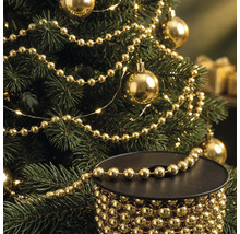 Kerstboom versierd met gouden parelslinger en kerstballen, met op de voorgrond een spoel met de gouden parelslinger.