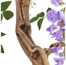 Detailopname van een kunstmatige blauweregen met een getextureerde houten stam, groene bladeren en paarse bloemen.