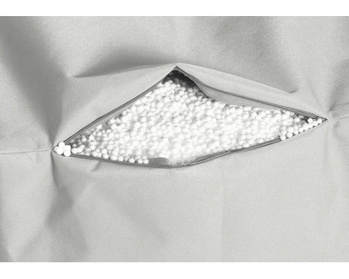 Detailopname van een ritssluiting in een stoffen hoes met een vulling van witte parels.