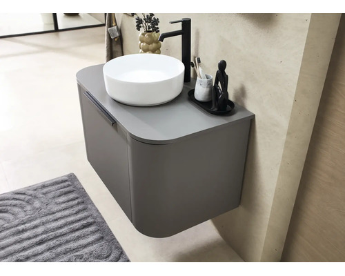 Hangend wastafelmeubel met afgeronde hoeken, een witte opzetwastafel en een zwarte kraan in een moderne badkamer.