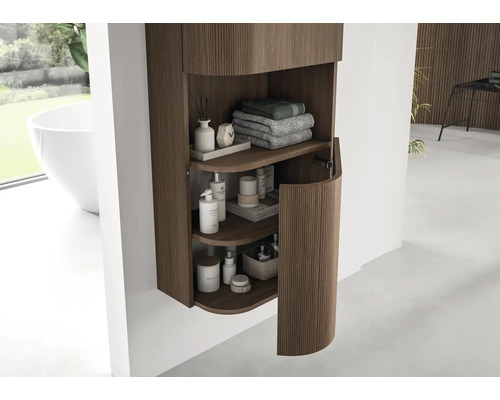 Moderne badkamer hangkast met verticale houten latten en een ronde deur, ingericht met handdoeken en verzorgingsproducten.