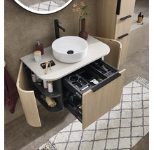 Modern badkamermeubel in houtlook met witte opzetwastafel, zwarte kraan en open lade met vakverdeling.