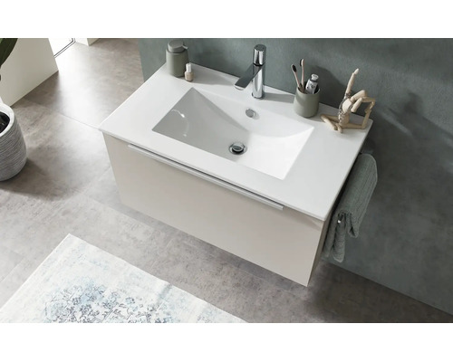 Modern wandhangend badkamermeubel met witte wastafel, beige onderkast en chromen kraan in een lichte badkamer.