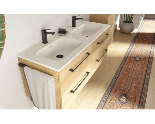 Moderne dubbele wastafel met onderkast in houtlook, vier lades met donkere grepen, twee witte wasbakken en zwarte kranen.