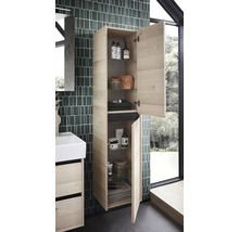 Wandhangende hoge badkamerkast in lichte houtlook met twee geopende deuren, glazen legplanken en badkameraccessoires naast een wastafelmeubel.