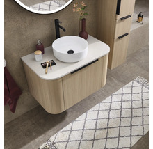 Moderne badkamer met geribbeld wastafelmeubel in houtlook, witte opzetwastafel, zwarte kraan en ronde verlichte spiegel.