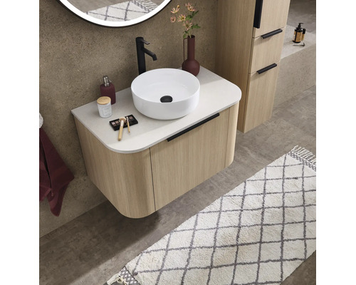 Moderne badkamer met geribbeld wastafelmeubel in houtlook, witte opzetwastafel, zwarte kraan en ronde verlichte spiegel.