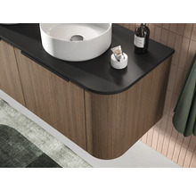 Moderne hangende wastafelonderkast met verticaal gegroefd front in houtlook, zwart blad en witte opzetwastafel.