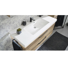 Modern badkamermeubel met witte wastafel, houten onderkast en zwarte kraan tegen een wand met zeshoekige tegels.