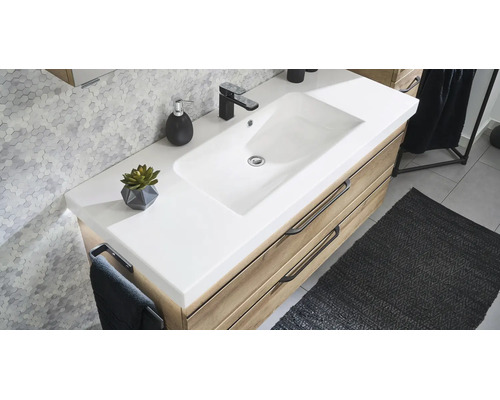 Modern badkamermeubel met witte wastafel, houten onderkast en zwarte kraan tegen een wand met zeshoekige tegels.