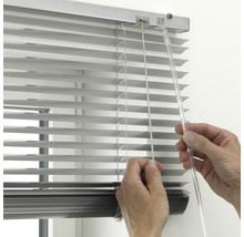 Detailopname van een hand die een zilveren aluminium jaloezie bedient met een transparante tuimelstaaf en trekkoord.