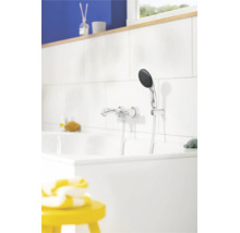 Verchroomde badkraan met handdouche op een witte tegelwand boven een wit ligbad in een lichte badkamer.