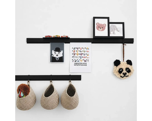 Twee zwarte wandplanken voor het opbergen van kinderkamerdecoratie, afbeeldingen en speelgoed, gecombineerd met hangende gevlochten manden.
